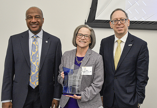 Amy Brooks-Kayal poses for a photo with Chancellor Gary S. May and Vice Chancellor of Human Health Sciences Mark I. Rosenblatt.
