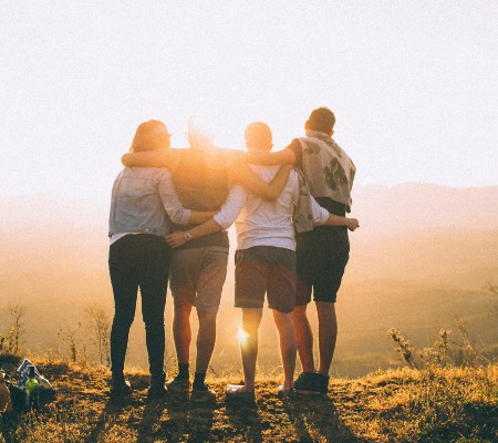 Four people lined up with their arms wrapped around their backs