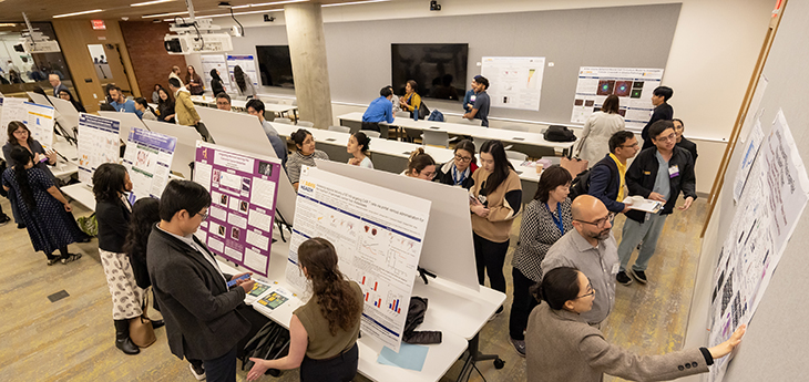 Overview of posters and presenters with people observing.