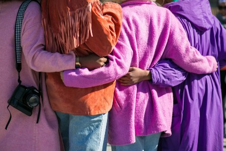 Four women wrapping their arms around one another in a circle