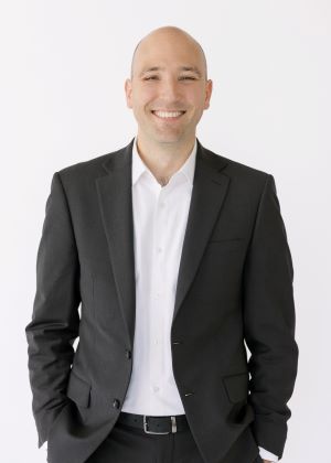 image of troels adrian wearing a dark suit, smiling with his hands in his pockets against a white background