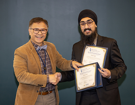 Two men stand side-by-side holding two certificates.