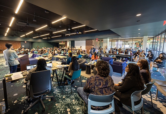 Large room filled with people and big screens.
