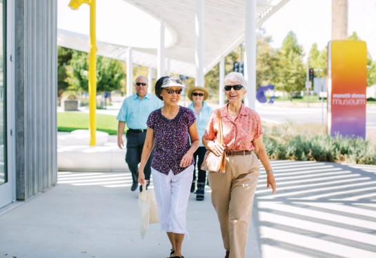a pair of women walking and chatting in front of the Manetti Shrem Museum