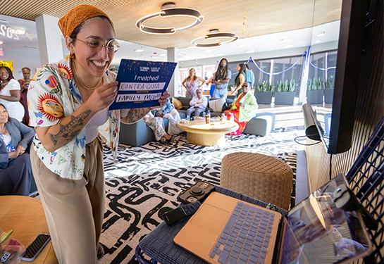 A medical student holds an “I Matched: Contra Costa Family Medicine” placard for her classmates to see in a video meeting.