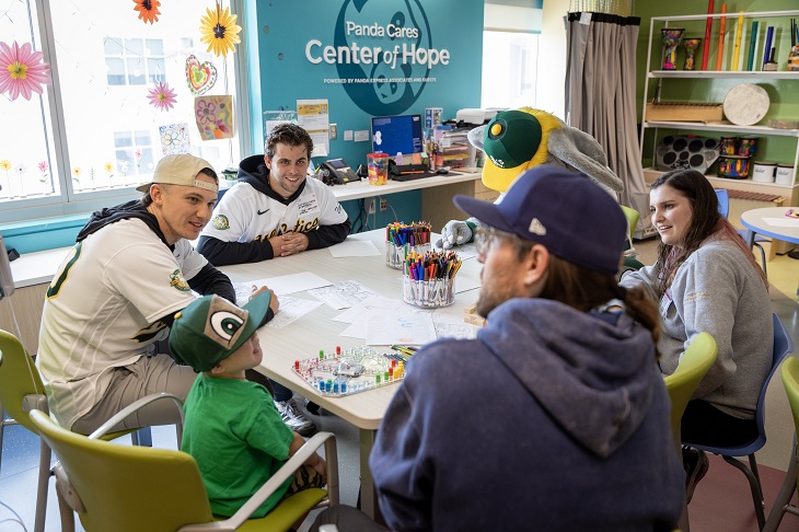 Two members of the A's color with pediatric patients.