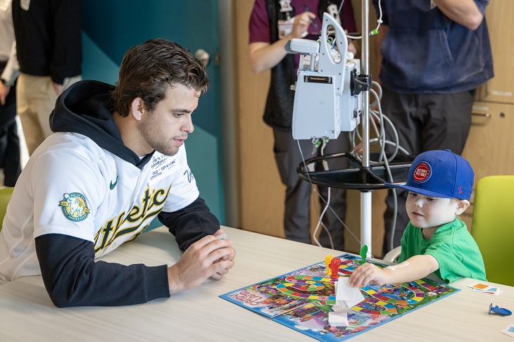An A's player plays a board game with a child.