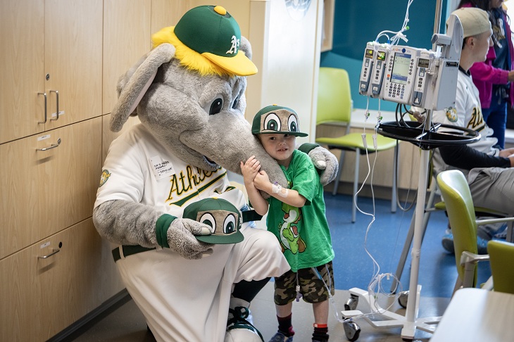 A pediatric patient hugs Stomper, the A's mascot.