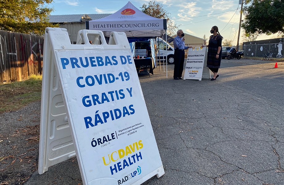 Spanish-language sign advertises free, rapid COVID‑19 testing by an outdoor registration tent in Knights Landing.