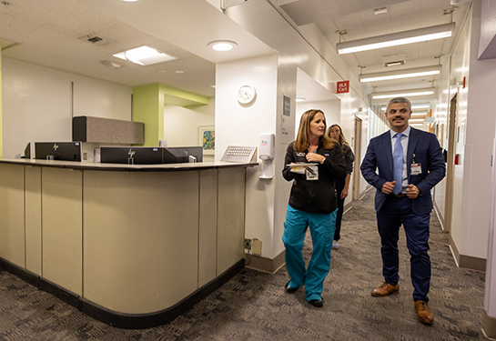 Three people walk together in a clinic hallway 