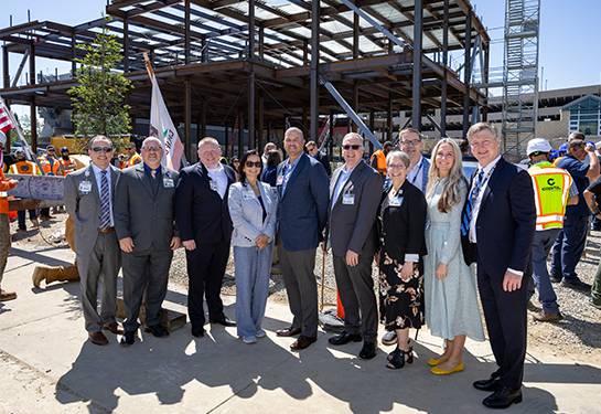 A group of UC Davis Health leadership pose together at the Central Utility Plant expansion construction site during a topping out ceremony.
