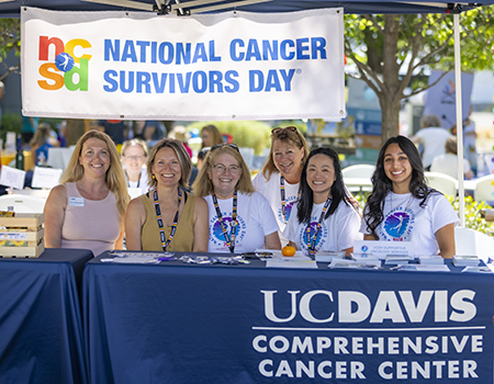 Six women sit under a sign that reads National Cancer Survivors Day