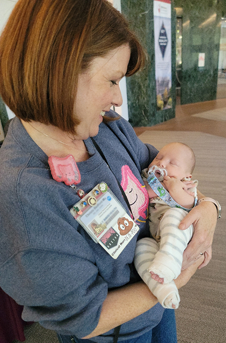 Red haired nurse holds baby in her arms as she cuddles him and looks down at him lovingly.