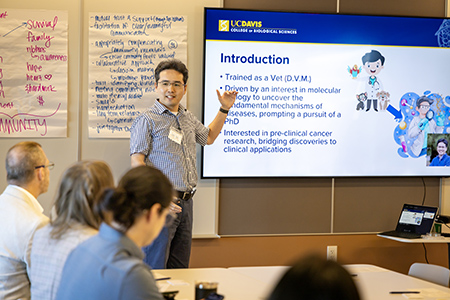 Man talking and pointing to slide presentation.