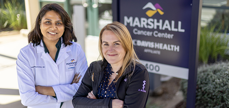 Two females standing next to Marshall Cancer Center sign