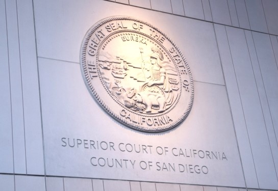 A round seal of the State of California on a grey-pink stone wall of a courthouse. 