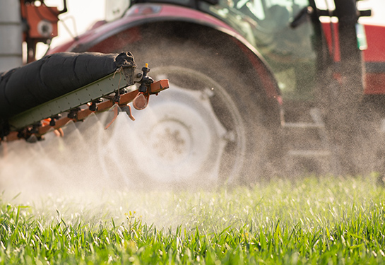 Tractor spraying pesticides over a green field