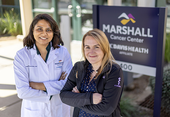 Two females standing next to Marshall Cancer Center sign