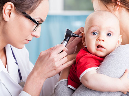 small child getting his ear examined by a pediatrician looking for signs of ear infection