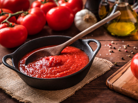 A bowl of tomato sauce with a wooden spoon