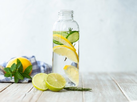 A glass bottle of water with lemon and lime slices