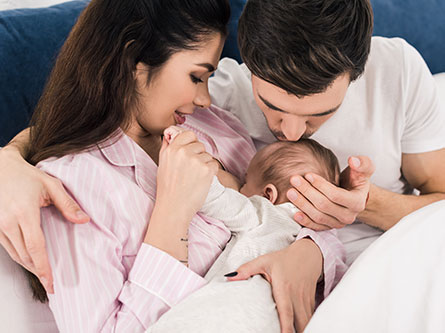 woman breastfeeding a baby with a man sitting next to her