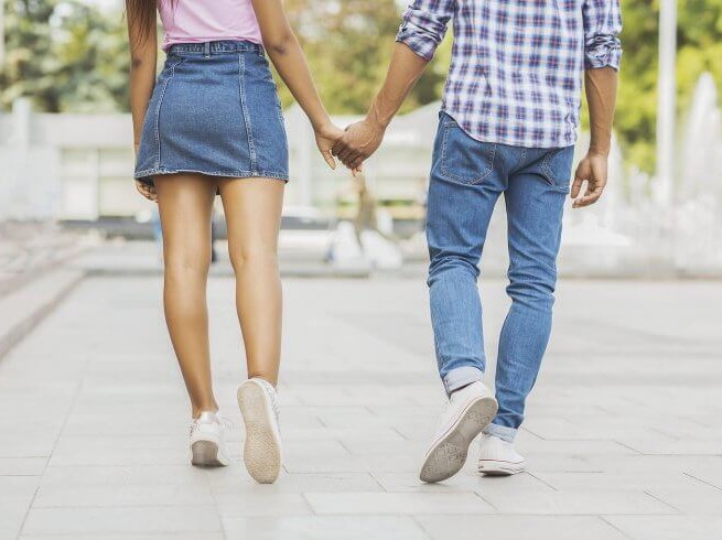two people holding hands walking away from camera