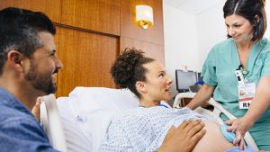Pregnant patient in labor in a hospital bed with nurse.