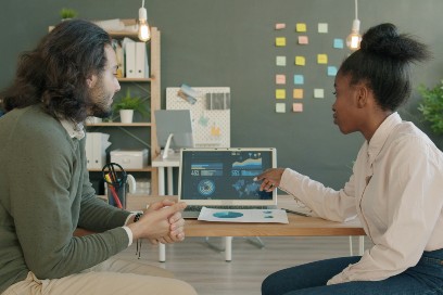 Two people looking at a laptop discussing what is shown