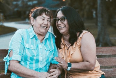 Two women sitting closely on a bench