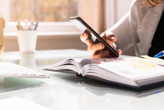 person looking at phone and personal calendar