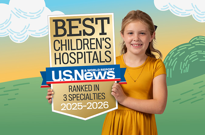 Niño sosteniendo una insignia de mejores Hospitales Infantiles clasificados en 3 especialidades por U.S. News