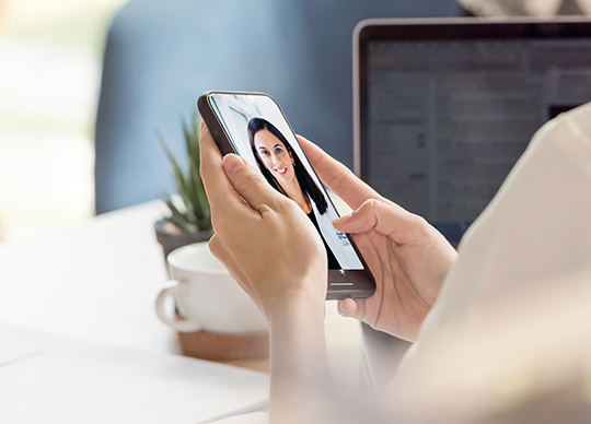 Person holding a phone during a video visit with a doctor