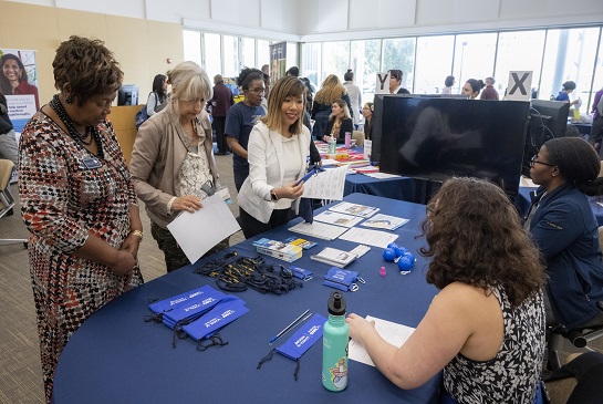 Principles of Community event attendees gather at a resource table to learn more