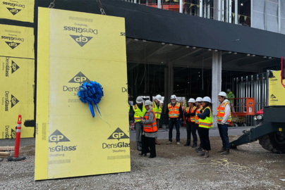 UC Davis leaders and construction team members watch the final pane lifted for installation on the 48 Complex.