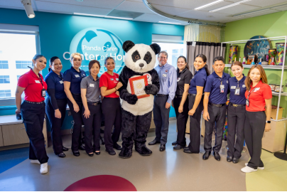 Staff and the Panda Cares mascot, Pei Pei, stand for a photo op at the opening of the Panda Cares Center of Hope.