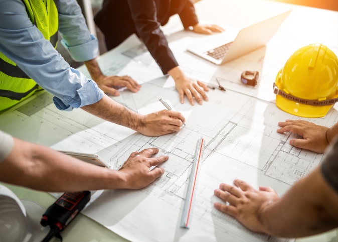 people gathered around blueprints at a construction site