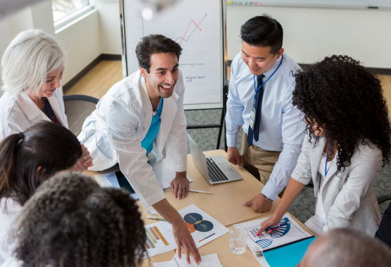 clinicians in discussion gathered around a table with documents