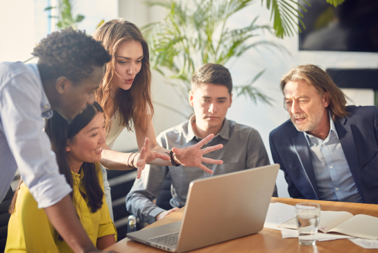 colleagues gathered around a computer in discussion