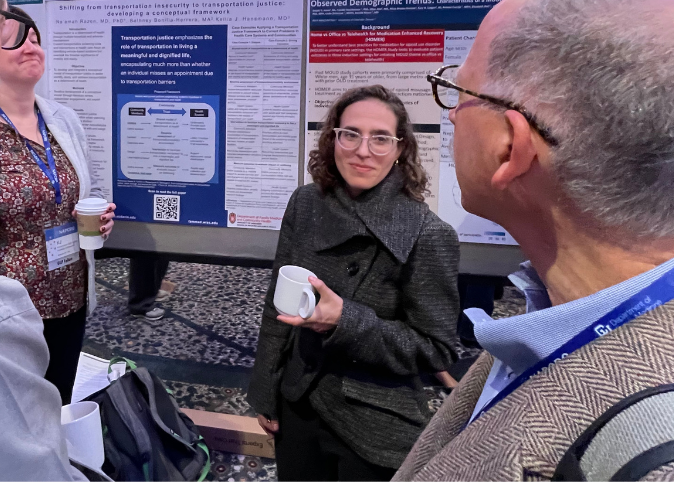 Na'amah Razon, a family medicine physician, stands next to her research poster and speaks with others.