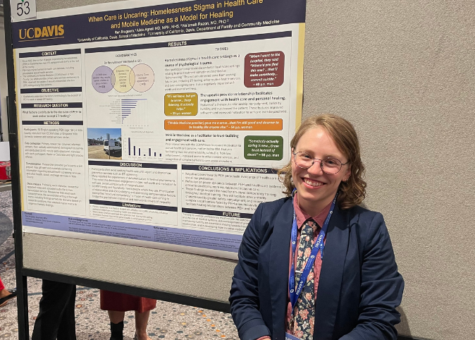 Ren Bruguera smiles next to a research poster at a national conference. 