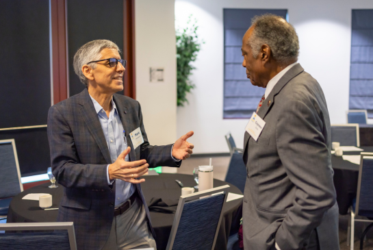 Two men in suits speak together during the Rev PC Summit.