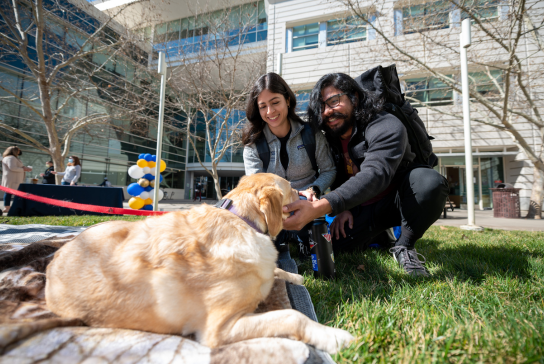 Two residents petting a golden retriever dog.