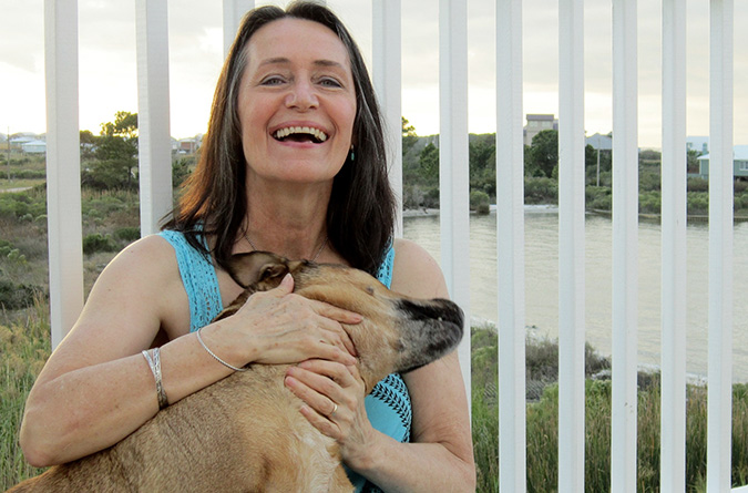 woman sitting on a porch hugging her dog.