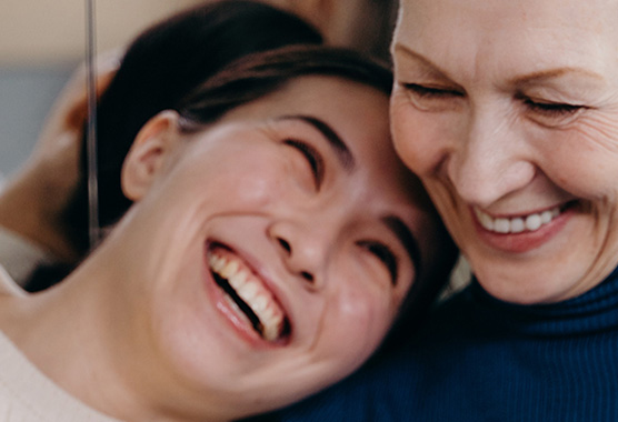 Elderly couple standing on a porch, holding flowers.