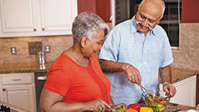 A man and woman preparing vegetables in a kitchen.