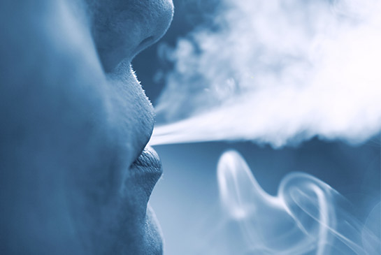 Person blowing smoke out of their mouth.