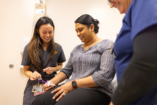 Nurse and provider smiling while assisting a patient.