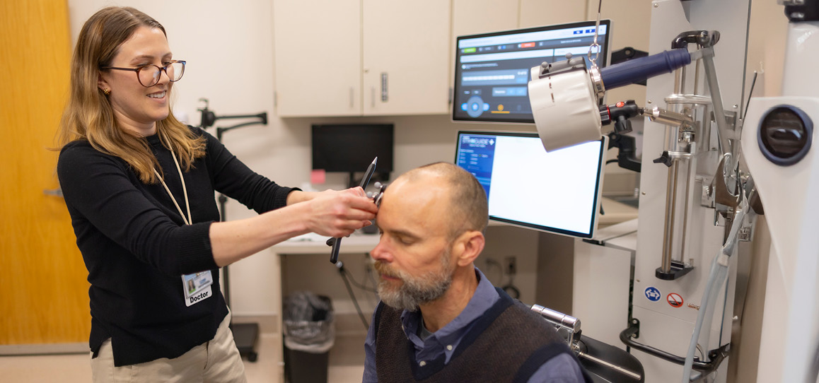 Psychiatrist Katharine Marder with a mock patient demonstrating the transcranial magnetic stimulation machine.