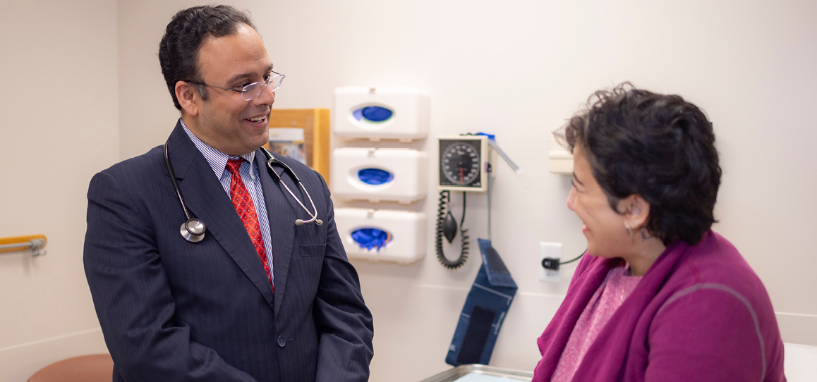 Rheumatologist Gaurav Gulati smiling next to a patient.